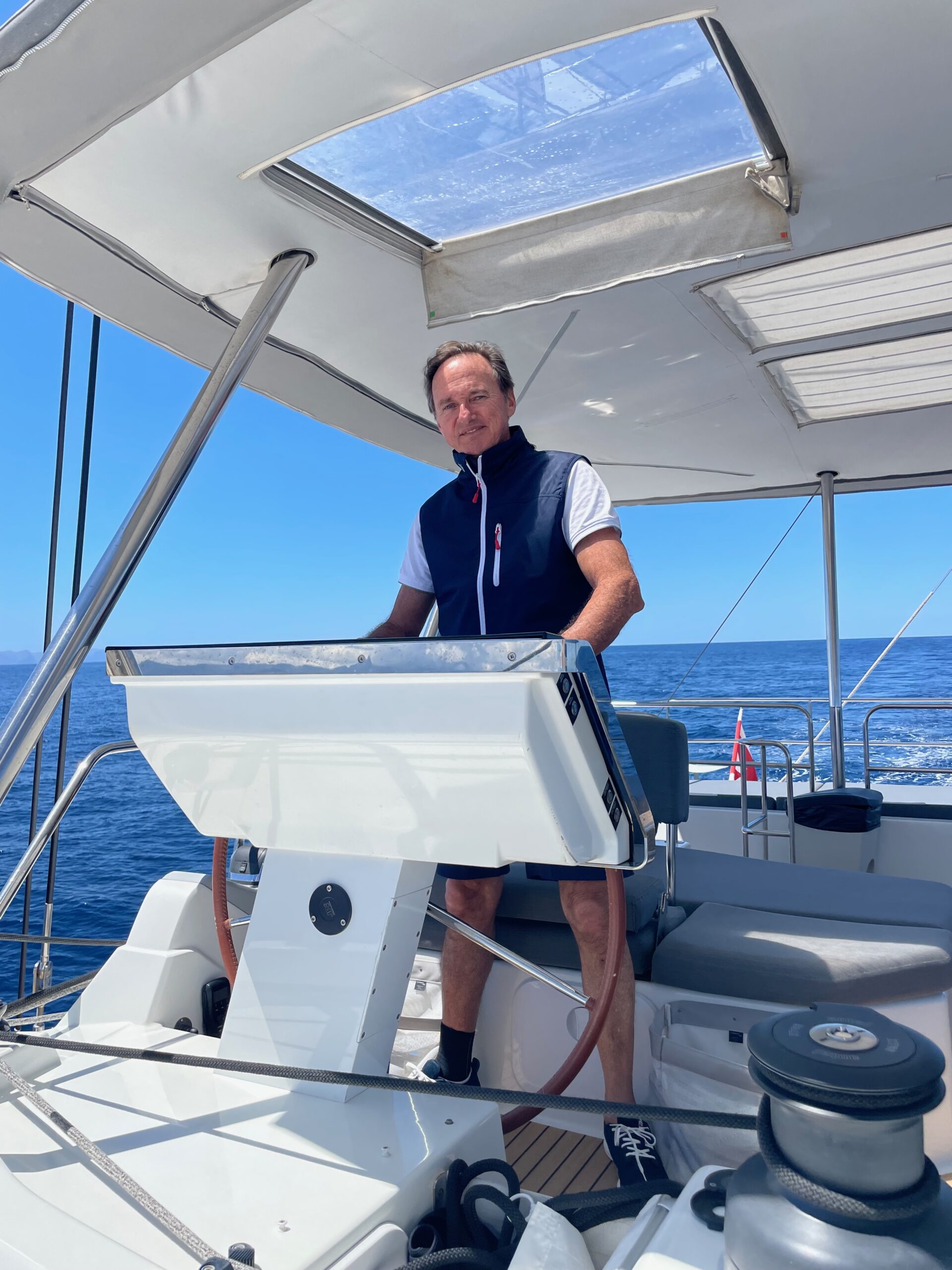 Captain Nacho Lamadrid at the helm of a luxury sailing catamaran during an offshore passage.