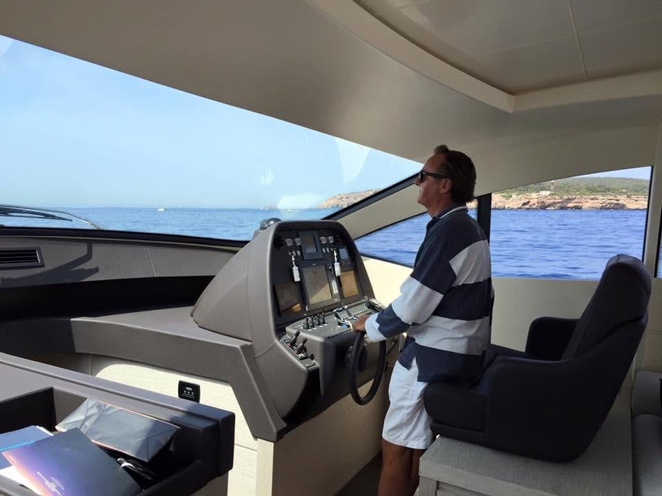 Professional yacht captain at the helm of a Pershing 64